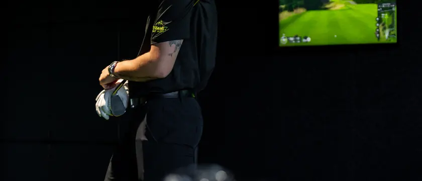 A coach standing in a bay at Summit Golf Academy.